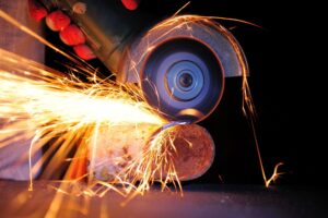 Worker cutting metal with grinder. Sparks while grinding iron